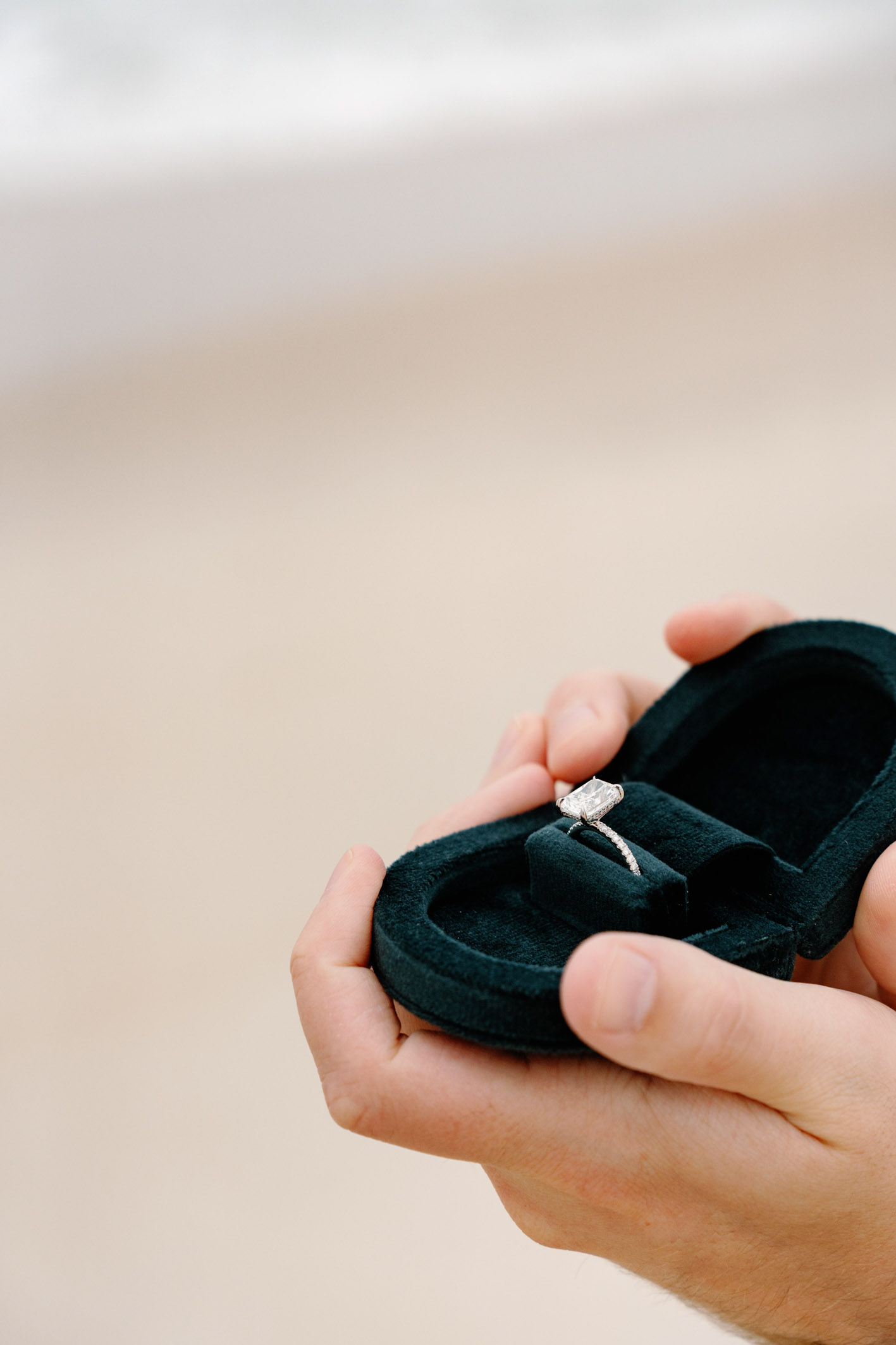a man's hand holding an engagement ring
