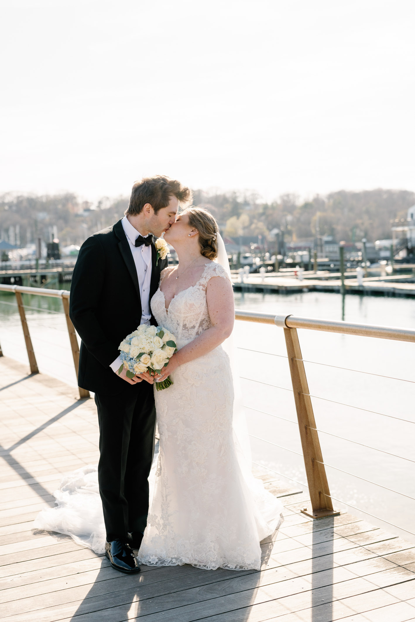 bride and groom kissing in front of the water in port jefferson